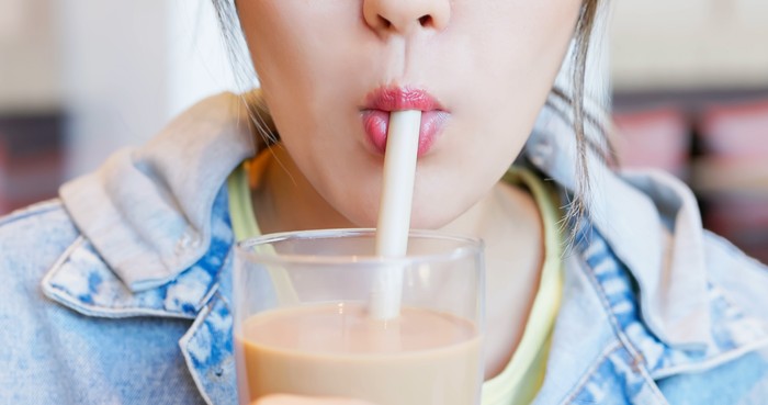 close up asian woman mouth enjoy drink taiwanese drink bubble milk tea in glass - she chew and stir tapioca pearls