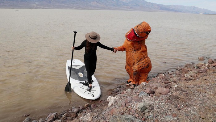 Garrett Dong, of Ventura, California, stands in an inflatable dinosaur costume at Lake Manly, a temporary lake formed by heavy rainstorms, at Death Valley National Park, California, U.S., February 24, 2024. The lake is located at Badwater Basin, which is the lowest point in North America at 282 feet below sea level. REUTERS/Ronda Churchill