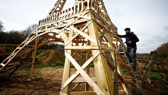 French carpenter Frederic Malmezac and Sylvain Bouchard, a sports enthusiast with disability, work on a 16-meter replica of the Eiffel Tower built from recycled wood which they hope to display along the path of the Olympic torch relay and on Olympic sites for the Paris 2024 Olympic and Paralympic Games, in La Chevroliere, near Nantes, France, February 19, 2024. REUTERS/Stephane Mahe