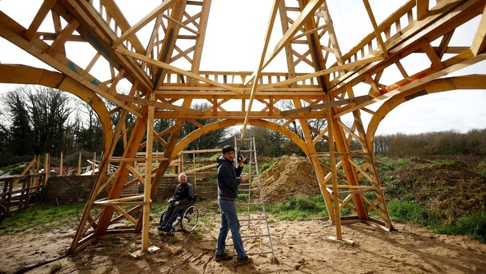 French carpenter Frederic Malmezac and Sylvain Bouchard, a sports enthusiast with disability, work on a 16-meter replica of the Eiffel Tower built from recycled wood which they hope to display along the path of the Olympic torch relay and on Olympic sites for the Paris 2024 Olympic and Paralympic Games, in La Chevroliere, near Nantes, France, February 19, 2024. REUTERS/Stephane Mahe