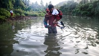 Seorang warga membantu siswa SD menyeberangi sungai di Desa Todowongi tersebut.