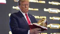 Kandidat presiden dari Partai Republik mantan Presiden Donald Trump memegang sepatu kets emas Trump di Sneaker Con Philadelphia, sebuah acara yang populer di kalangan kolektor sepatu kets, di Philadelphia pada Sabtu, 17 Februari 2024.