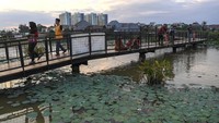 Sejumlah warga berjalan di atas jembatan di Taman Malaka Asri, Rorotan, Jakarta Utara, Senin (26/2/2024).  