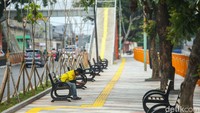 Di taman tersebut, ada kursi panjang, area duduk yang terbuat dari semen, jembatan penyeberangan orang (JPO), pot tanaman, dan pembatas pagar menghadap jalan dan kali. 