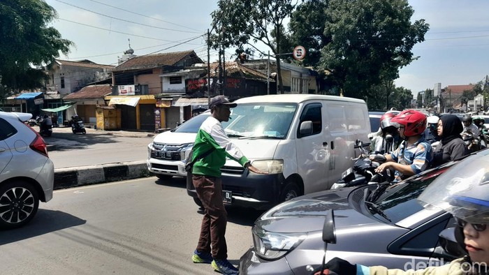 Seorang sukarelawan penjaga perlintasan, Ajat Supri terlihat sedang mengatur lalu lintas di Jalan Garuda.