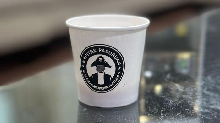 Wajah Gus Irsyad di logo Kapiten Pasuruan pada cup kopi dicoreti.