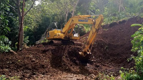 Ekskavator membersihkan material longsor di ruas jalan di Desa Gurung, Kecamatan Welak, Manggarai Barat, NTT, pada Rabu (28/2/2024).