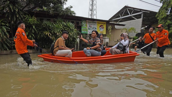 Perumahan di Serang Banjir, Warga Berangkat Kerja Naik Perahu Petugas BPBD (Badan Penanggulangan Bencana Daerah) Provinsi Banten mendorong perahu saat menolong warga melewati banjir di Kompleks Perumahan Pakupatan Kota Serang, Banten, Rabu (28/2/2024). Banjir tersebut terjadi di sejumlah titik di Serang akibat hujan deras sejak Selasa (27/2) malam dan diperburuk oleh banyaknya saluran drainase yang tersumbat tertimbun sampah. ANTARA FOTO/Asep Fathulrahman/nym.