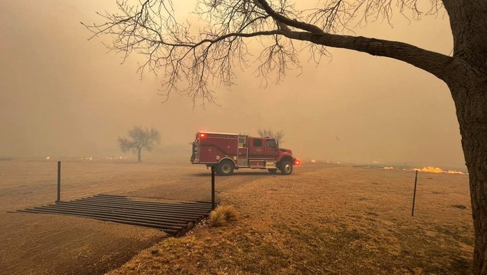 Cars drive as smoke and fire rise from wildfires in a location given as Texas, U.S., in this handout picture released on February 27, 2024. Greenville Fire-Rescue/Handout via REUTERS  THIS IMAGE HAS BEEN SUPPLIED BY A THIRD PARTY. MANDATORY CREDIT. NO RESALES. NO ARCHIVES.