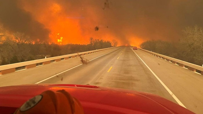 Potret Horor Kebakaran Hutan di Texas yang Semakin Meluas Cars drive as smoke and fire rise from wildfires in a location given as Texas, U.S., in this handout picture released on February 27, 2024. Greenville Fire-Rescue/Handout via REUTERS THIS IMAGE HAS BEEN SUPPLIED BY A THIRD PARTY. MANDATORY CREDIT. NO RESALES. NO ARCHIVES.