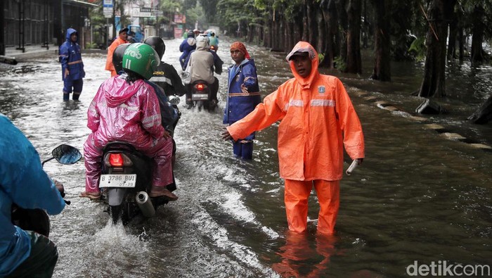 Sejumlah petugas mengatur lalu lintas di jalan Raya Kelapa Nias, Kelapa Gading, Jakarta Utara, Kamis (29/2/2024). Petugas PPSU dan SDA membantu lalu lintas saat banjir serta memberi tahu  informasi titik-titik banjir kepada pegendara.