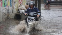 Seorang pengendara motor saat menerobos banjir.