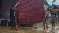Warga yang rumahnya kebanjiran berjibaku mengeluarkan bendar berharga yang berada di dalam rumah agar tidak ikut terseret arus.