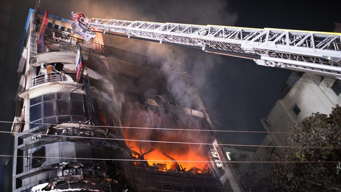 Bangladesh Fire People watch as firefighters work to contain a fire that broke out at a commercial complex in Dhaka, Bangladesh, Thursday, Feb. 29, 2024. Bangladesh's health minister says a fire in a six-story commercial complex in the nation's capital, Dhaka, has killed several people and injured dozens of others. (AP Photo/Mahmud Hossain Opu)