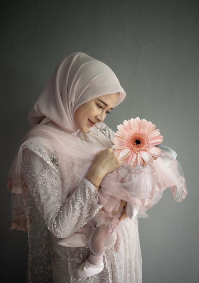 Bella tampil cantik dan bersahaja memakai dress panjang warna blush pink. Dress tampak mewah dengan aksen lace, bordir dan tulle. Sang buah hati pun mengenakan busana bertema senada. Foto: Instagram/@denny_caknan @bellabonita_r.a