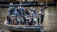 Sejumlah pengendara sepeda motor menggunakan perahu eretan menyeberangi Sungai Kali Angke di Kecamatan Penjaringan, Jakarta, Jumat (1/3/2024).