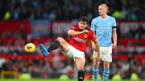 MANCHESTER, ENGLAND - OCTOBER 29: Harry Maguire of Manchester United passes the ball whilst under pressure from Erling Haaland of Manchester City during the Premier League match between Manchester United and Manchester City at Old Trafford on October 29, 2023 in Manchester, England. (Photo by Michael Regan/Getty Images)