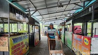 Salah satu pedagang minuman sedang melintasi stan makan dan minuman yang terlihat sepi oleh pedagang dan pembeli.
