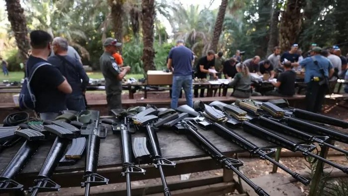 Israelis arrive at a weapons distribution point for people allowed to carry arms, at the Ayyelet HaShahar Kibbutz, in northern Israel, near the Lebanese border on October 12, 2023. (AFP)
