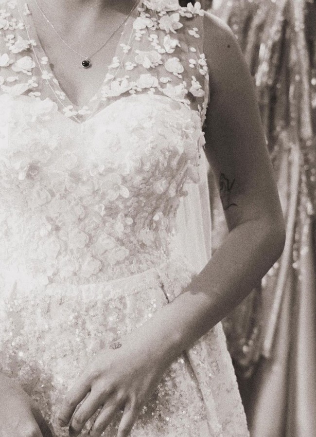 Gaun pengantin yang dicoba Karin sendiri tampak simpel namun terlihat elegan dengan dipenuhi aksen-aksen bunga yang juga berwarna senada. Gaun tersebut tak berlengan sehingga membuat tato di tangannya terlihat. Foto: Instagram/@narinkovilda