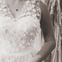 Gaun pengantin yang dicoba Karin sendiri tampak simpel namun terlihat elegan dengan dipenuhi aksen-aksen bunga yang juga berwarna senada. Gaun tersebut tak berlengan sehingga membuat tato di tangannya terlihat. Foto: Instagram/@narinkovilda