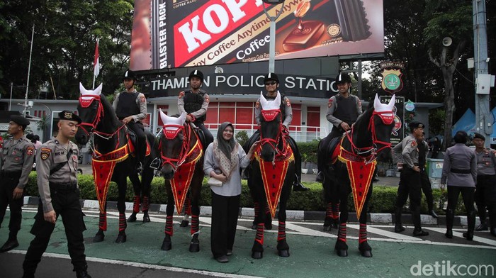 Sejumlah warga berfoto dengan pasukan polisi berkuda di CFD Bundaran HI, Jakarta, Minggu (3/3/2024).