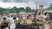 Dua pria memandangi puing-puing 29 kamar kos yang terbakar.