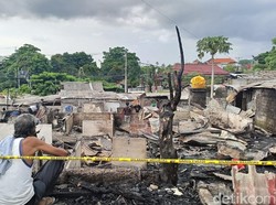 Dua pria memandangi puing-puing 29 kamar kos yang terbakar.
