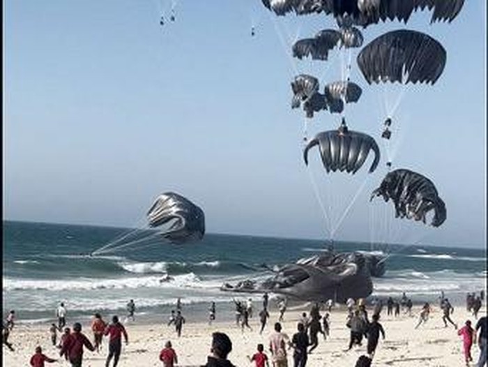 This image grab from an AFPTV video shows Palestinians running toward parachutes attached to food parcels, air-dropped from US aircrafts on a beach in the Gaza Strip on March 2, 2024. Israels top ally the United States said it began air-dropping aid into war-ravaged Gaza on March 2, as the Hamas-ruled territorys health ministry reported more than a dozen child malnutrition deaths. (Photo by AFP)
