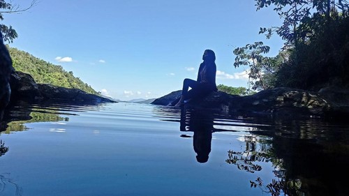 Seorang wisatawan duduk di pinggir Kolam di Atas Awan di puncak Air Terjun Cunca Rii di Desa Wae Lolos, Kecamatan Sano Nggoang, Manggarai Barat, NTT. (Foto: Istimewa)