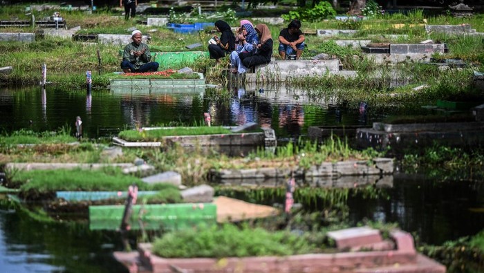 Umat Islam berdoa di depan makam keluarga dan kerabat dekat yang terendam banjir di Tempat Pemakaman Umum Semper, Jakarta, Minggu (3/3/2024). Sepekan jelang datangnya bulan suci Ramadhan, sejumlah umat Islam yang melakukan tradisi ziarah makam untuk mendoakan keluarganya. ANTARA FOTO/ Rivan Awal Lingga/YU