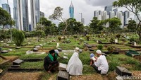 Warga membawa bunga serta berdoa di atas pusara anggota keluarga yang sudah meninggal.  