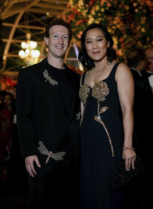 Mark Zuckerberg tampil elegan dalam balutan jas hitam-hitam. Terlihat ada detail menarik di busananya, bordiran berbentuk capung dengan kilauan kristal. Istri Zuck, Priscilla Chan, pun tampil senada memakai gaun hitam berpotongan simple namun tampak glamor berkat hiasan emas bentuk bunga. Foto: Reliance group via AP