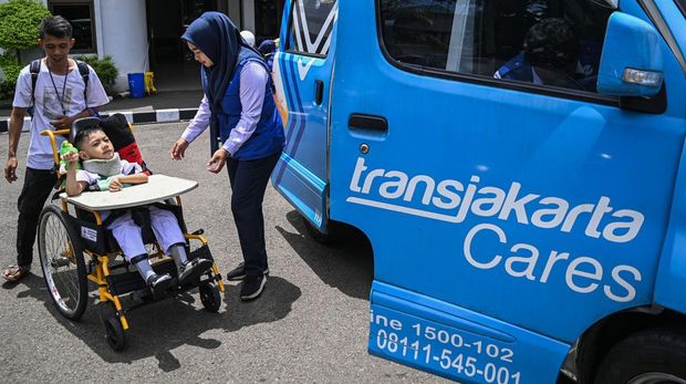 Seorang petugas membantu warga dan anaknya penyandang disabilitas bersiap menaiki mobil Transjakarta Care usai sekolah di halaman Sekolah YPAC Jakarta, Senin (4/3/2024). PT Transjakarta memiliki 20 unit mobil Transjakarta Care yang siap melayani secara gratis bagi warga penyandang disabilitas hingga lansia yang membutuhkan transportasi. ANTARA FOTO/Sulthony Hasanuddin/Spt.