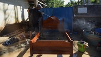 Seorang warga membersihkan tempat tidurnya yang terendam lumpur.