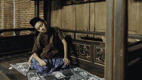 young muslim praying worship of the Allahs kindness  at  joglo house. Muslim children are doing prayers according to Islamic principles