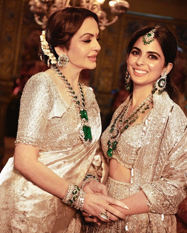 Istri Mukesh Ambani, Nita dan putrinya Isha tampil glamour selama upacara Hastakshar untuk Anant. Keduanya memakai saree Kanchipuram dan lehenga bercahaya, yang disempurnakan dengan kalung perhiasan berlian dan zamrud. Foto: Instagram