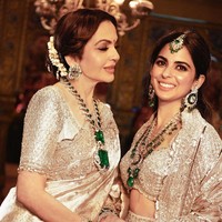 Istri Mukesh Ambani, Nita dan putrinya Isha tampil glamour selama upacara Hastakshar untuk Anant. Keduanya memakai saree Kanchipuram dan lehenga bercahaya, yang disempurnakan dengan kalung perhiasan berlian dan zamrud. Foto: Instagram
