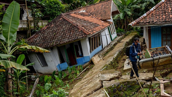 Seorang pewarta foto melintas di samping bangunan sekolah yang rusak dampak pergerakan tanah di Desa Cibedug, Kecamatan Rongga, Kabupaten Bandung Barat, Jawa Barat, Selasa (5/3/2024). Pusat Vulkanologi dan Mitigasi Bencana Geologi (PVMBG) memprediksi pergerakan tanah yang menghancurkan 10 rumah dan 192 kk mengungsi tersebut tidak akan meluas karena sudah terlokalisir dengan batas rekahan tanah yang berbentuk tapal kuda. ANTARA FOTO/Raisan Al Farisi/aww.