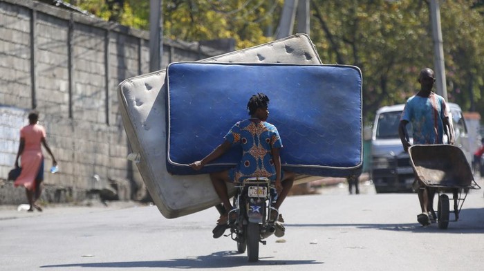 Potret Kepanikan Warga Haiti Saat Gengster Lepaskan Ribuan Napi dari Penjara Residents transport mattresses on a motorcycle in Port-au-Prince, Haiti, Monday, March 4, 2024. Authorities ordered a 72-hour state of emergency starting Sunday night following violence in which armed gang members overran the two biggest prisons and freed thousands of inmates over the weekend. (AP Photo/Odelyn Joseph)