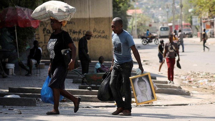 Residents carry water jugs to avoid scarcity at home as the government declared a state of emergency amid violence, in Port-au-Prince, Haiti, March 4, 2024. (REUTERS/Ralph Tedy Erol)  REFILE - CORRECTING ACTION FROM 