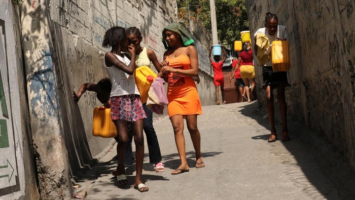 Residents carry water jugs to avoid scarcity at home as the government declared a state of emergency amid violence, in Port-au-Prince, Haiti, March 4, 2024. (REUTERS/Ralph Tedy Erol)  REFILE - CORRECTING ACTION FROM 