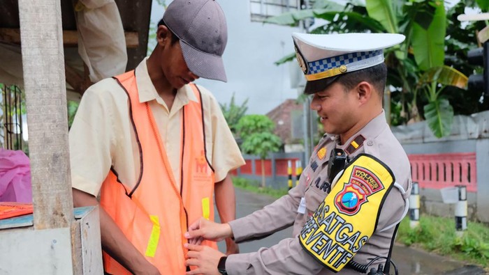 Satlantas Polres Malang memberikan bantuan keselamatan kepada relawan perlintasan kereta api.