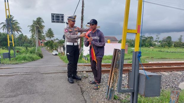 Satlantas Polres Malang memberikan bantuan keselamatan kepada relawan perlintasan kereta api.