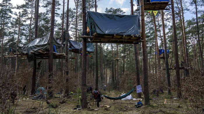 Aktivis Bangun Rumah Pohon untuk Tolak Ekspansi Pabrik Tesla di Jerman A view of tree houses set up by activists near the Tesla Gigafactory for electric cars in Gruenheide near Berlin, Germany, Tuesday, March 5, 2024. Production at Tesla's electric vehicle plant in Germany came to a standstill and workers were evacuated after a power outage that officials suspect was caused by arson. The interior ministry in the state of Brandenburg says unidentified people are suspected of deliberately setting fire to a high-voltage transmission line on a power pylon. (AP Photo/Ebrahim Noroozi)