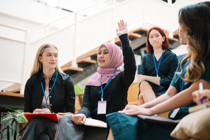 Asian Malay female is raising hand during a seminar in board room.