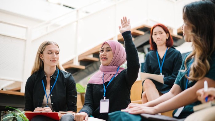 Asian Malay female is raising hand during a seminar in board room.