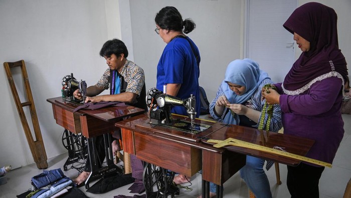 Pelatihan menjahit bagi penyandang disabilitas Orang tua memakaikan pakaian hasil pelatihan menjahit kepada anak penyandang disabilitas dengan didampingi seorang instruktur penyandang tuna daksa (kiri) di Gedung ABK UMKM, Tangerang Selatan, Banten, Rabu (6/3/2024). Pelatihan menjahit yang diikuti oleh anak penyandang disabilitas bersama orang tuanya tersebut dilakukan untuk meningkatkan keterampilan dan mengasah motorik melalui pemanfaatan kain bekas untuk dijadikan pakaian layak pakai. ANTARA FOTO/Sutlhony Hasanuddin/rwa.