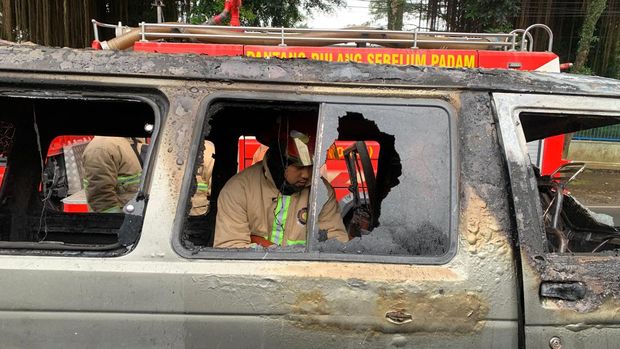 PMK tengah melakukan pendinginan mobil Daihatsu Zebra yang terbakar di Kota Malang.