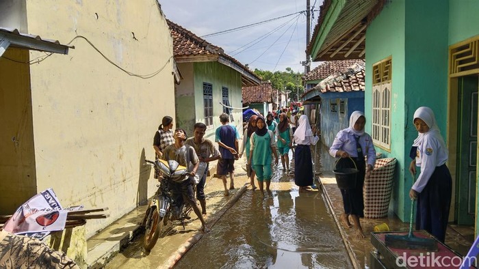 Warga Kuningan tengah membersihkan dampak banjir.